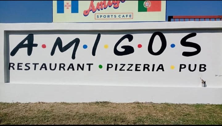 Hand-painted A·M·I·G·O·S Restaurant Pizzeria Pub signage across the exterior wall of the building