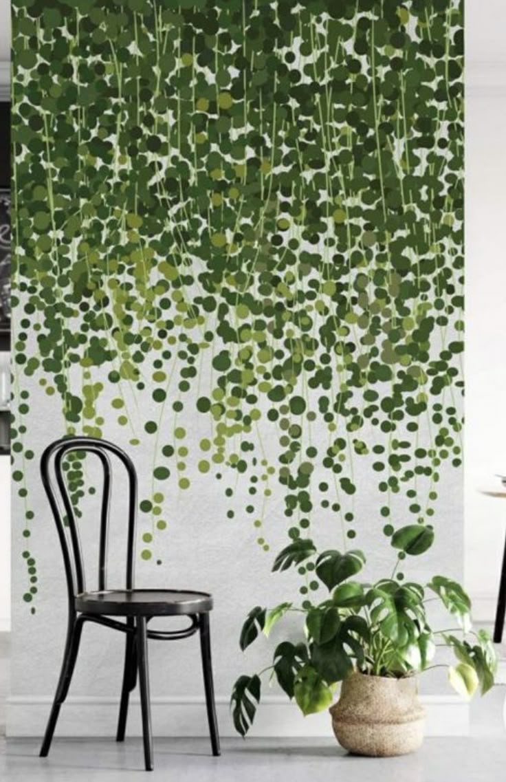 Hand-painted cascading green vine and leaf mural falling down a white feature wall behind a black bentwood chair and potted plant