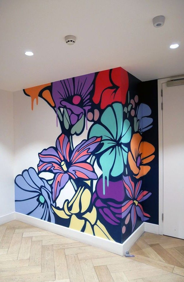 Oversized hand-painted floral mural in saturated purple, red, orange and teal running across a white interior feature wall