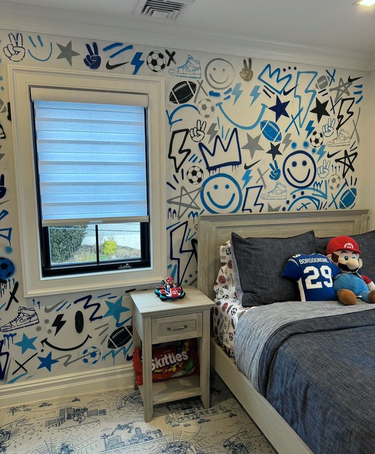 Blue and black hand-drawn doodle graffiti mural covering a child's bedroom wall, with a bed and sports-themed bedding