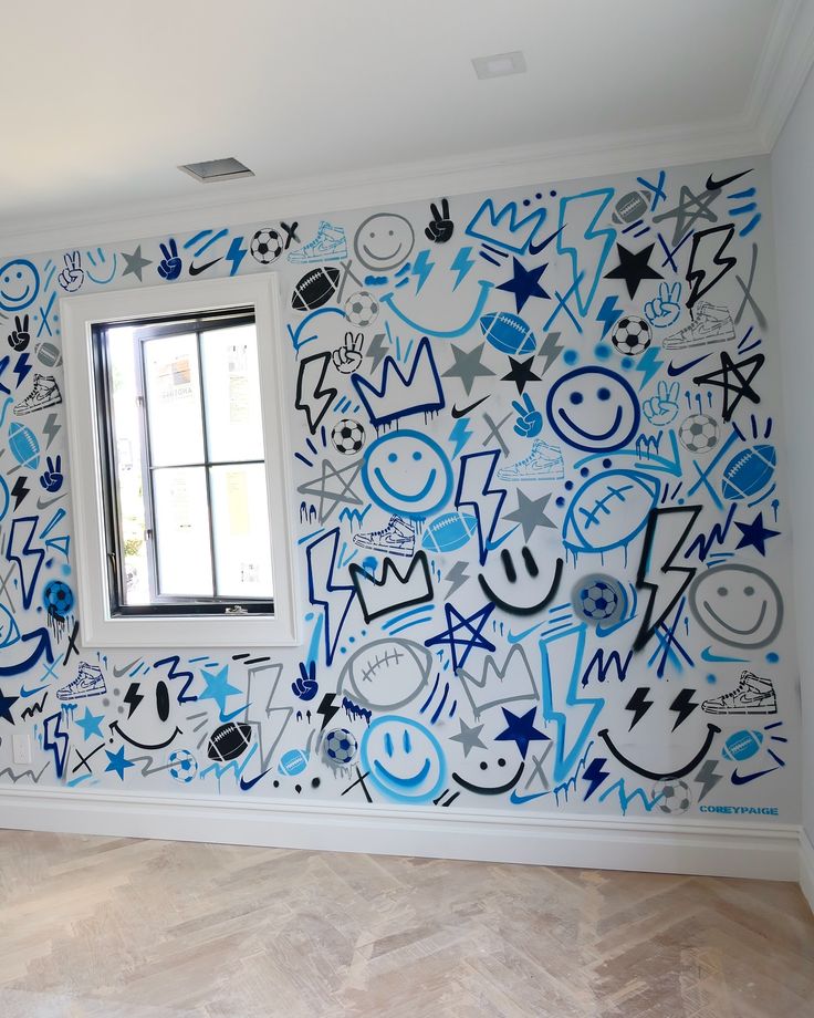 Full wall of hand-drawn blue and black doodles including footballs, smiley faces, stars and lightning bolts, above a herringbone timber floor