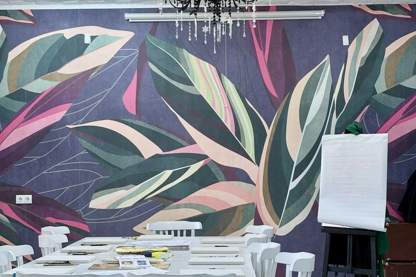 Large hand-painted botanical leaf mural in deep plum, sage and blush covering a full interior feature wall